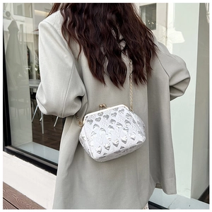 Detail of silver evening clutch with heart jacquard pattern and golden chain strap