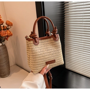 Detail einer beigen Stroh-Beuteltasche mit hochwertigen braunen Ledergriffen und Besatz