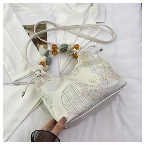 Détail d'un sac à main fleuri avec poignée en perles et design élégant de style chinois