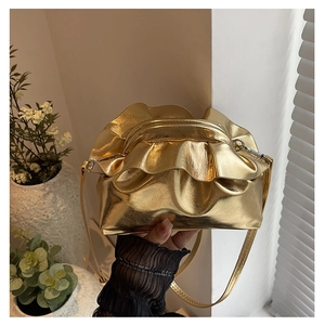 Detailed macro shot of the golden metallic ruched handbag with distinctive pleats