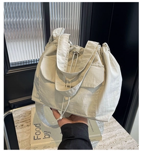 Vue détaillée du sac seau en nylon crème avec cordon de serrage et poche frontale
