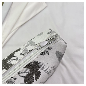 Detail shot of the durable silver zipper and floral embroidery on the white fabric bag