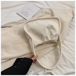 Close-up of beige corduroy shoulder bag texture with soft pleats and a wide strap