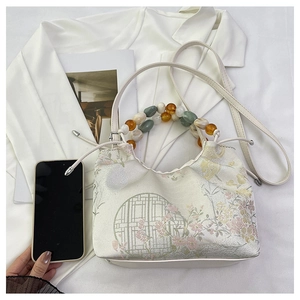 Détail du sac à main blanc de style chinois avec motifs floraux et poignées perlées