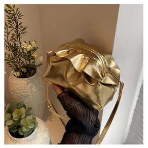 Detail view of the metallic gold pleated crossbody bag with a soft texture and slim strap