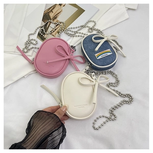 Detalle de minibolsos bandolera ovalados en rosa, azul denim y blanco roto con cadenas