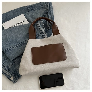Close-up of beige canvas and brown leather bucket bag with front pocket in casual lifestyle setting