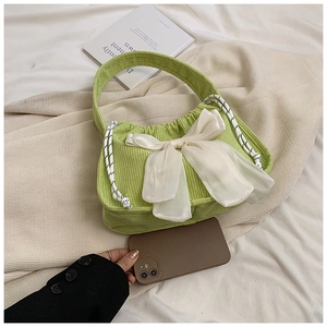 Top view of green corduroy handbag with large white bow and striped drawstring closure