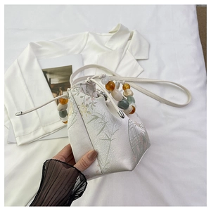 Gros plan du sac seau en satin avec motifs bambou et anse en perles colorées