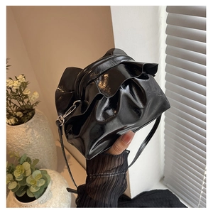 Detail of black glossy pleated shoulder bag with metallic clasp and fine leather texture