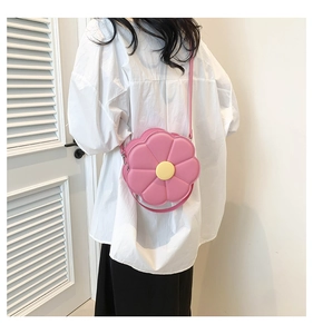 Roze crossbodytas in de vorm van een zonnebloem met geel hart gedragen door een model