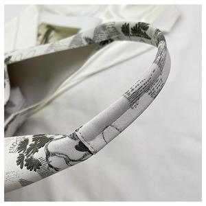 Detailed close-up of retro Toile de Jouy floral embroidery on a premium fabric bucket bag