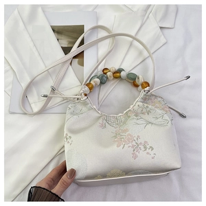 Détail du sac en satin floral avec poignée en perles colorées et bandoulière réglable