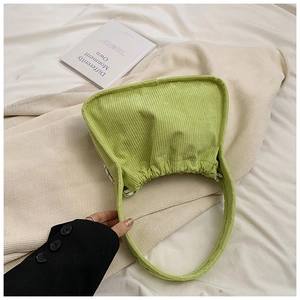 Close-up of light green corduroy handbag with vertical ribbed texture and soft fabric finish