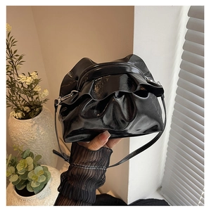 Detail of glossy black drawstring cloud bag with ruffles and slim shoulder strap