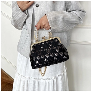 Close-up of black evening bag with silver heart patterns and gold floral handle