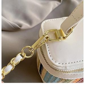 Close-up of golden metal buckle and white leather handle on a woven contrast bag
