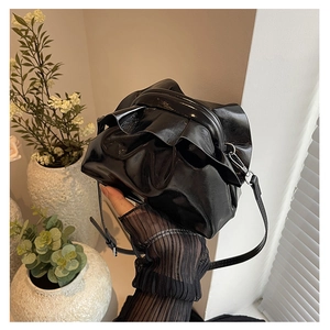 Detailed close-up of glossy black pleated cloud bag with silver hardware and leather strap