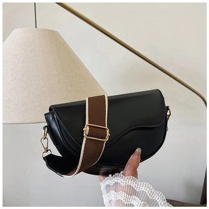 Macro shot of black saddle bag featuring matte PU leather and adjustable fabric shoulder strap