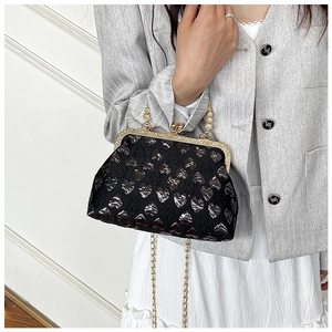 Close-up of black evening bag with heart embossing and vintage gold clasp handle