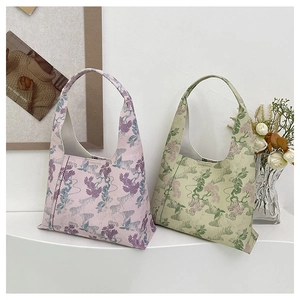 Detail view of pink and green floral embroidered hobo bags on a minimalist display stand
