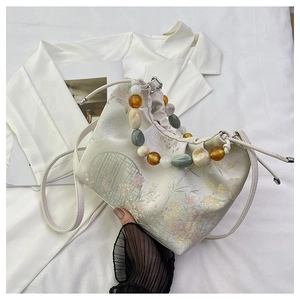 Détail du tissu en brocart floral et de l'anse en perles colorées d'un sac à main chinois
