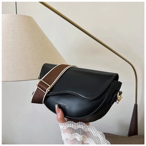 Detail of black faux leather saddle bag with adjustable wide fabric strap and gold hardware