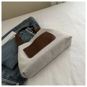 Close-up of beige canvas bucket bag with brown leather handles and aesthetic minimalist design