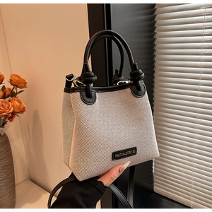 Nahaufnahme der Canvas Strohtasche mit Lederbesatz und Markenlogo-Detail