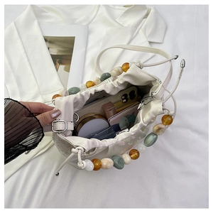 Vue de dessus de l'intérieur du sac seau crème avec téléphone, parfum et perles marbrées