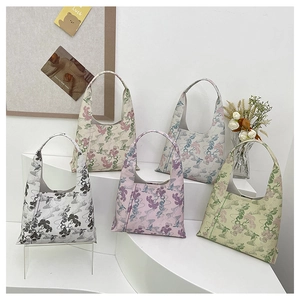 Detail view of five canvas hobo bags featuring oriental floral embroidery on a white stand