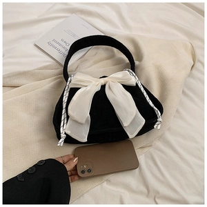 Detail of black corduroy handbag with a large white satin bow and woven drawstring