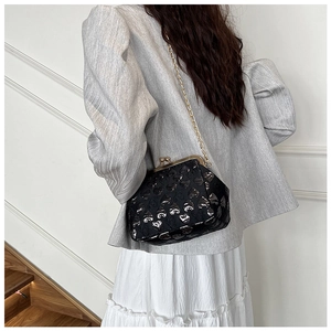 Detail of black heart-patterned evening bag with vintage gold clasp and chain strap