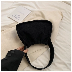Close-up of black corduroy hobo bag featuring elegant pleats and half-moon shape detail