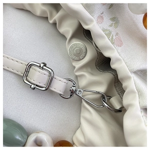 Détail de la bandoulière en cuir litchi blanc avec boucle argentée et doublure fleurie