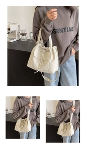 Détail du sac seau beige à cordon avec poche avant et bandoulière dans un décor lifestyle