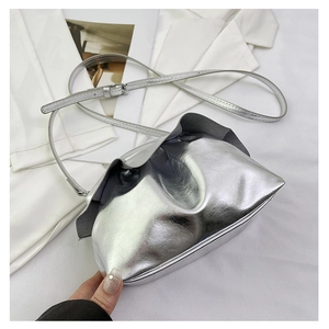 Detail of silver metallic cloud bag with gathered folds and adjustable shoulder strap