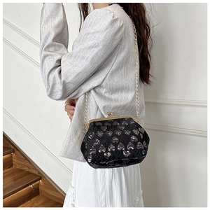 Detail of black heart pattern crossbody bag with gold chain and metal kiss-lock closure
