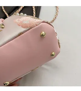 Close-up of golden metal studs on the bottom of pink floral embroidered silk bucket bag