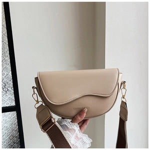 Detail of beige saddle bag with wavy flap design and wide brown textile strap
