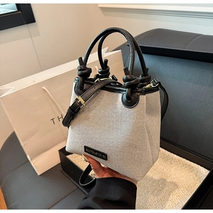 Detailansicht der Stroh-Eimertasche mit Canvas-Nähten und eleganten Knotengriffen