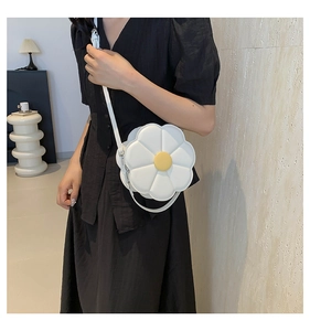 Detail van witte PU-lederen zonnebloemtas crossbody gedragen over een zwarte jurk