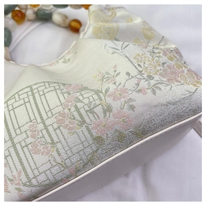 Détail du tissu à broderie florale chinoise et de la poignée en perles colorées