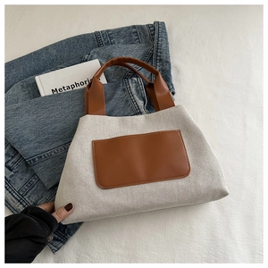 Detail of cream canvas and brown leather stitching on a stylish trapezoid bucket handbag