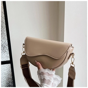 Detailed shot of beige leather saddle bag with wide woven strap and gold hardware