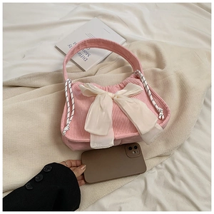 Detail of pink corduroy handbag featuring a large satin bow and side drawstring decor