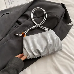 Detalle de bolso nube plateado con textura metálica fruncida y detalles de asa trenzada
