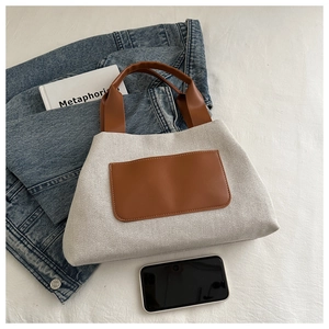Close-up of contrast canvas bucket bag featuring premium brown leather pockets and neat stitching