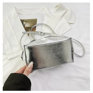 Detail of silver metallic crossbody bag showing textured finish and adjustable strap