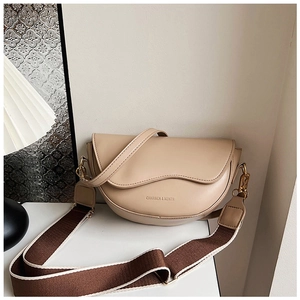 Close-up of beige half-moon saddle bag with striped canvas strap and gold hardware